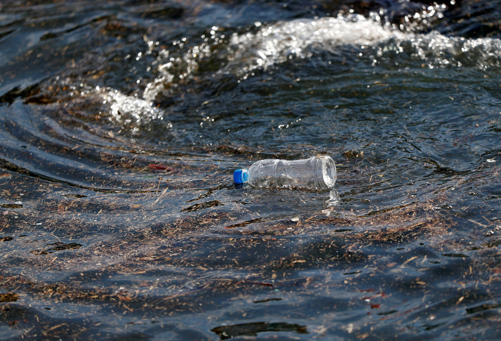 FILE PHOTO: A plastic bottle drifts on the waves of the sea at a fishing port in Isumi